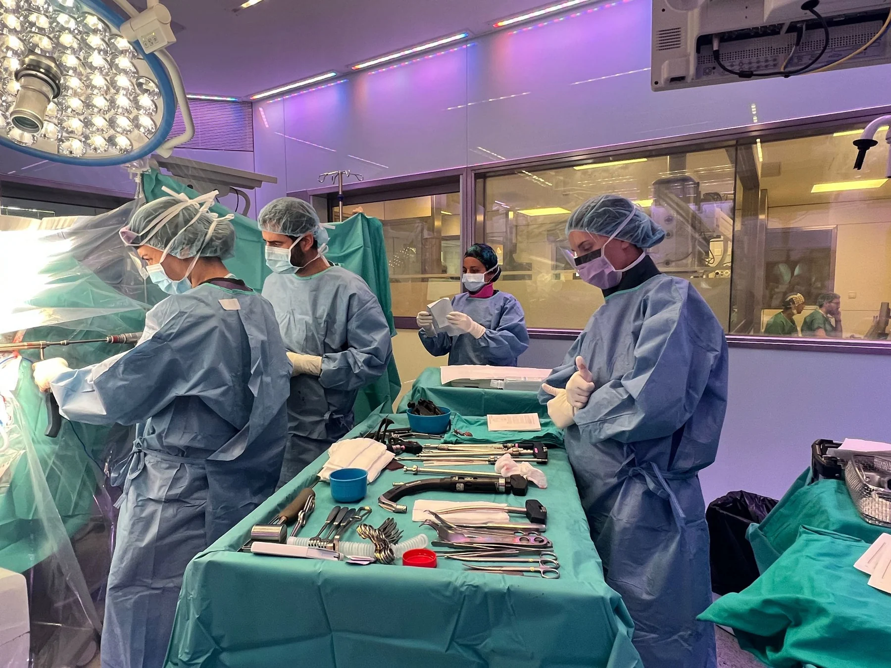 Staff wearing surgical attire beside an instrument table